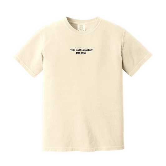 A cream-colored short-sleeve t-shirt with black text reading 'THE OAK ACADEMY EST 1996' printed on the center chest, displayed on a clean white background.