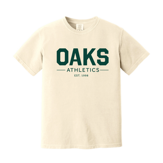 A cream-colored short-sleeve t-shirt with 'OAKS ATHLETICS EST. 1998' printed in dark green on the front, displayed against a solid white background.